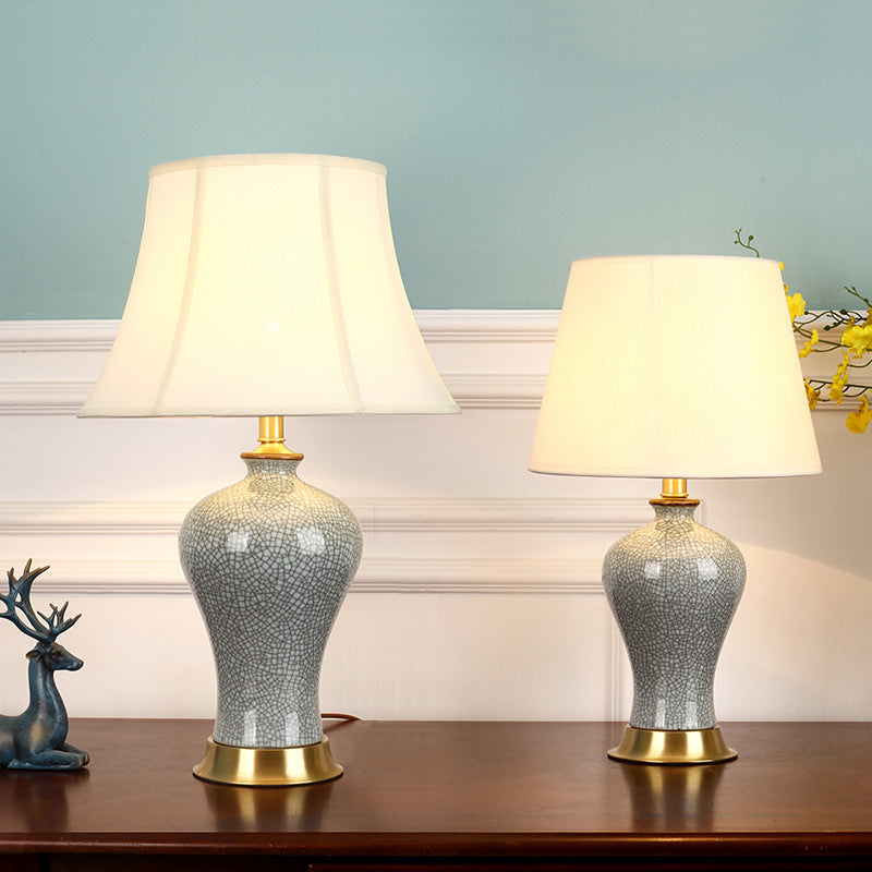 Bedside table lamp with warm amber glow and neutral fabric shade