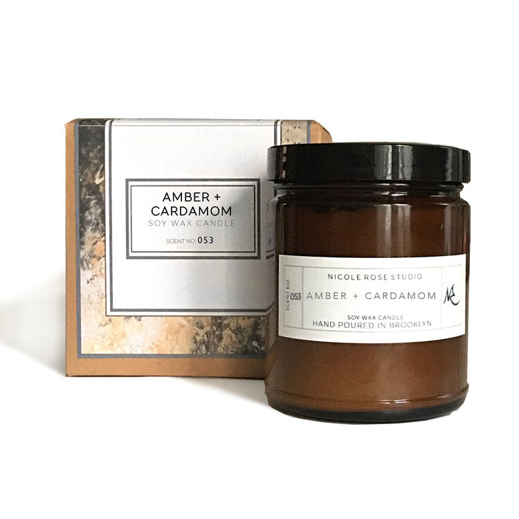 Amber and cardamom soy candle in a small gold tin with a plain white label