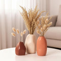Three small rustic ceramic bud vases with textured matte finish in neutral earthy tones